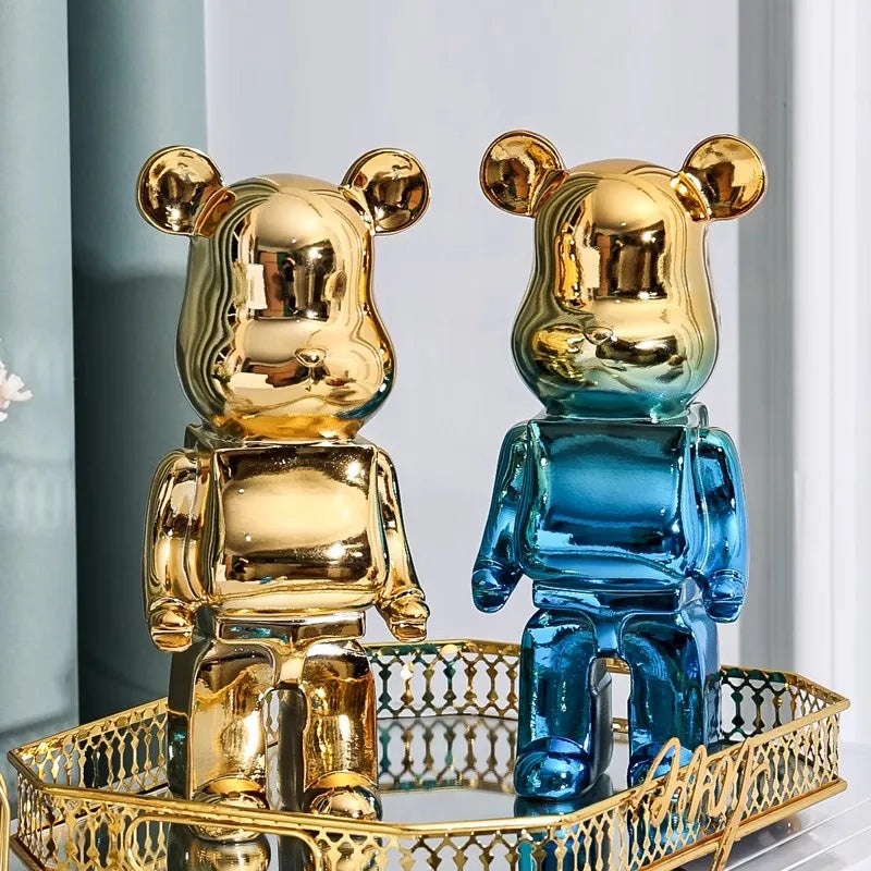 Five blocky bear sculptures in gold, checkerboard, silver, and black finishes arranged on a shelf