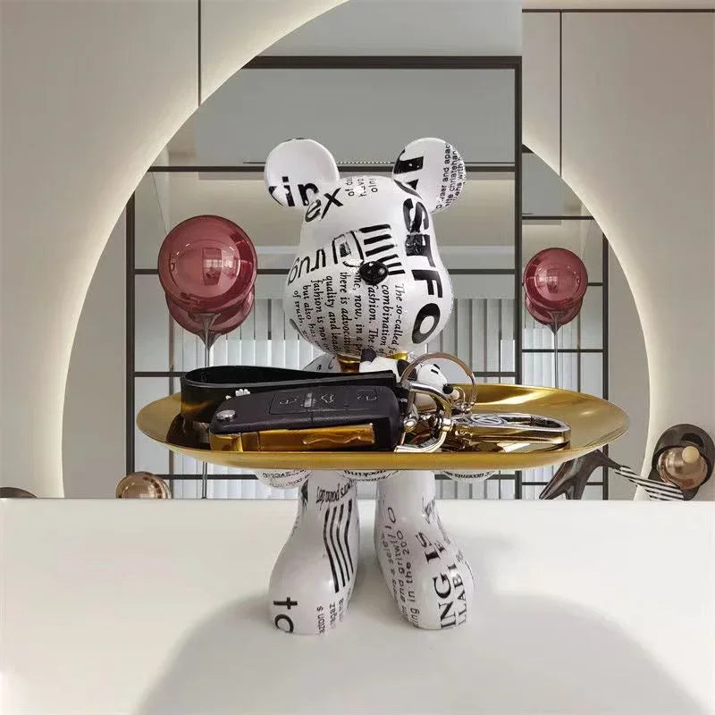 Black and white checkerboard-pattern bear sculpture with X-shaped eyes on a gold display tray
