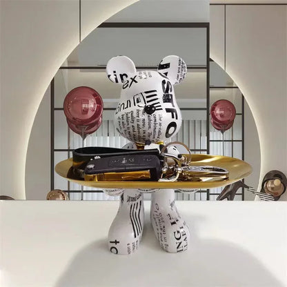 Black and white checkerboard-pattern bear sculpture with X-shaped eyes on a gold display tray