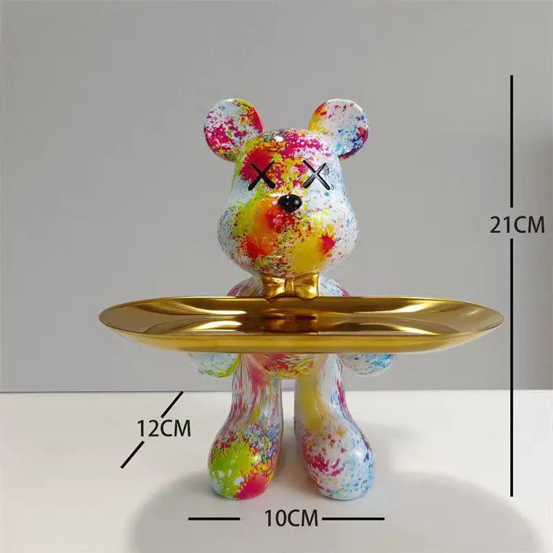 White bear sculpture with colorful paint-splash finish on a gold tray, isolated on white background