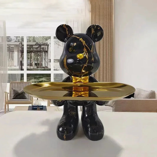 Black graffiti-finish bear sculpture displayed on a gold pedestal tray, mirrored vanity backdrop